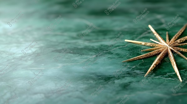 An image of golden metallic elements forming a ten-pointed star placed on a dark green marble surface with grey veins. The star is intricately detailed and stands out against the elegant marble background.