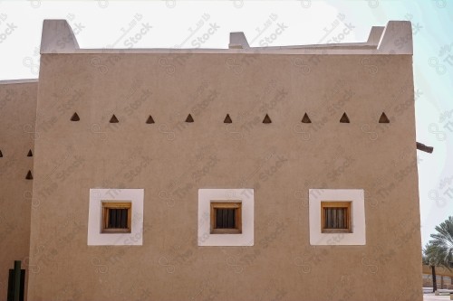 A heritage building built in the Najdi style, with a group of windows surrounded by white paint during the day