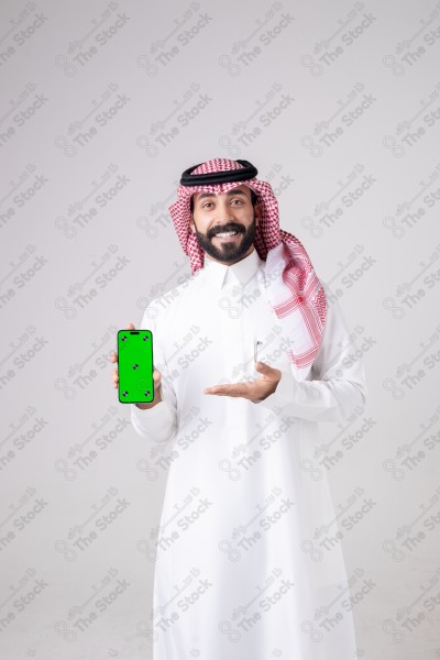 Portrait of a Saudi man holding a phone, pointing at the phone and making different expressions - green screen