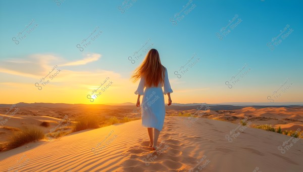 A woman in a long white dress walks on sand dunes in the desert during sunset. The sky is clear with warm sunset colors, and the golden sands stretch into the background.