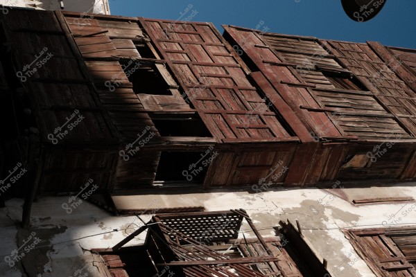 An old building with deteriorating wooden doors and windows under a clear sky.