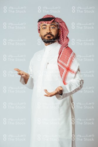 بورتريه رجل سعودي يرتدي الزي السعودي التقليدي يشير بكلتا يديه بينما يعبر وجهه عن التعجب والإستغراب