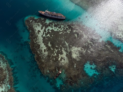 An aerial shot of the coral reefs in Shuaiba in one of the shores of the city of Jeddah, showing the wrecked ships beside the beach, the clear sea water.