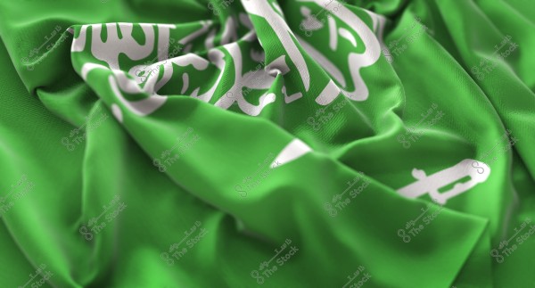 Image of the Saudi Arabian flag, showing the flag with soft folds and prominent features of white writing and design on a green background.
