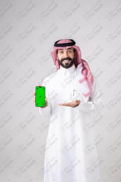 Portrait of a Saudi man holding a phone, pointing at the phone and making different expressions - green screen