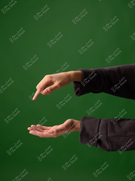 يد تشير إلى جهة الأسفل وأخرى مفتوحة فوق خلفية خضراء.