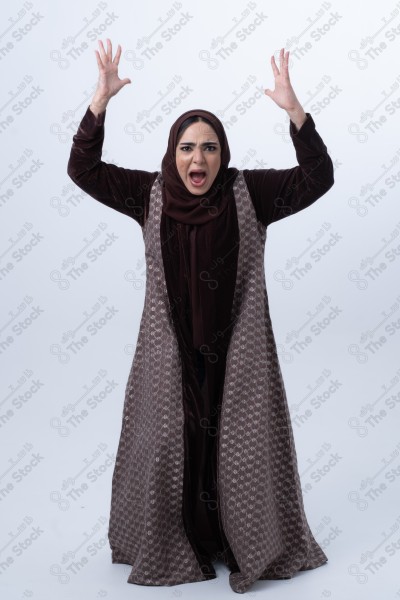 A young Saudi woman wearing an abaya and hijab, looking angry