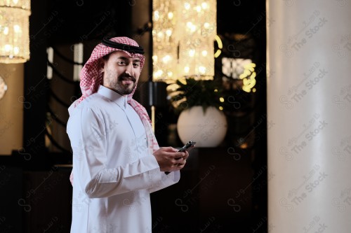 شاب سعودي في استقبال فندق ويقوم بتفاعلات متعددة ، ويظهر بيده حقيبة السفر