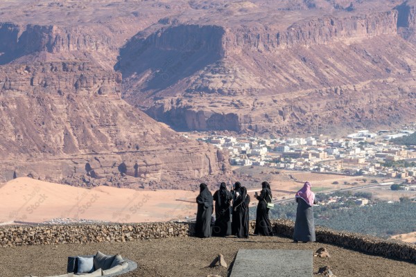 An aesthetic shot of people at the highest mountain peak in Al-Ula Governorate, Saudi Arabia, tourist places in Saudi Arabia, green palm tree farms.