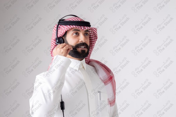 بورتريه رجل سعودي يلبس سماعة الرأس ويقوم بالتواصل عبر السماعة - خدمة العملاء ، مكالمة هاتفية