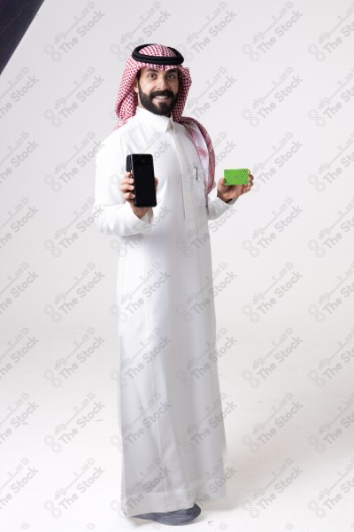 Portrait of a Saudi man holding an automatic payment device and a card and making different expressions