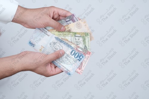 رجل سعودي يحمل النقود بيديه، جمع التبرعات للمحتاجين، مجموعة من الأوراق النقدية