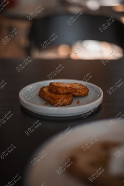 شريحتان من الخبز المحمص مغطاتان بالعسل موضوعتان على طبق أبيض فوق طاولة.