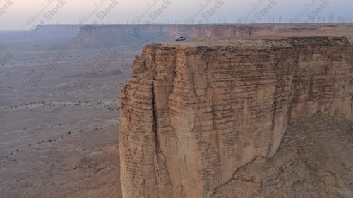 لقطة جوية لمجموعة سياح على جبل من جبال طويق المسمى بحافة العالم. سلسلة من الجبال الصخرية