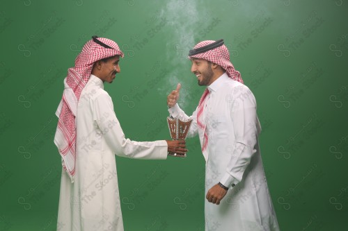 رجل سعودي يرتدي الزي السعودي التقليدي يقدم المبخره لضيفه في أحد المناسبات