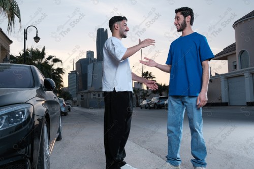 A snapshot of two young Saudis chatting and having fun on the road, their features showing joy and happiness.