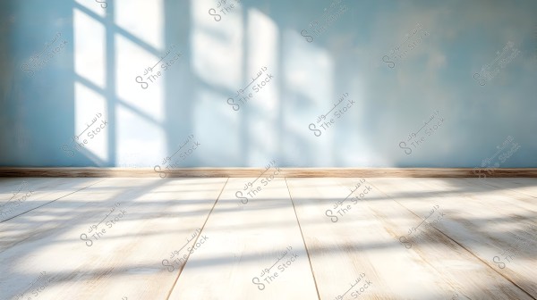 An image of a sunlit room showing the shadows of a large window cast on a light blue wall and a light-colored wooden floor. The wood planks run horizontally with a natural texture, and the sunlight creates a warm and serene atmosphere in the space.