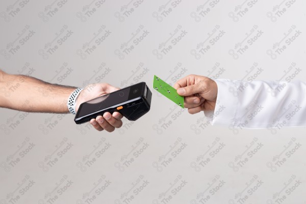 Portrait of a Saudi man holding a card and making automatic payments on a white background