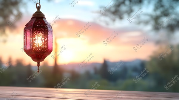 An ornate red metal lantern is hanging in the air, glowing with the light of the sunset in the background. A scenic landscape is visible with warm colors ranging from orange to pink, giving the image a serene and peaceful feeling.