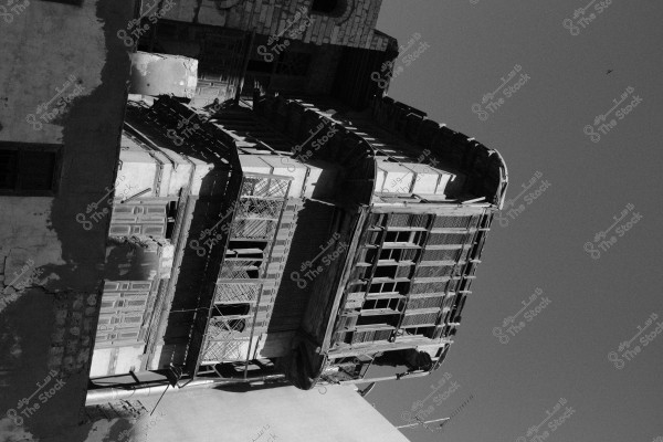 Black and white image of an old house with a decorative wooden facade and protruding windows in a traditional architectural design.