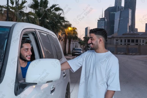 shot of two young Saudis chatting and having fun on the road, their features showing joy and happiness.