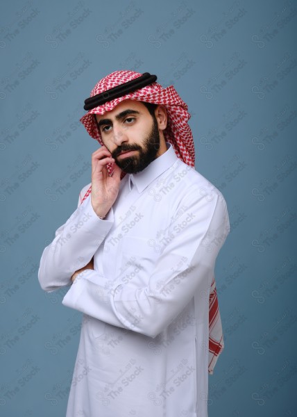 بورتريه شاب سعودي يرتدي الزي السعودي بتعابير وجه غاضبة وملامح جادة ،على خلفية سماويه