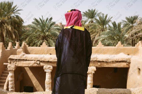 لقطة لرجل سعودي يرتدي الزي التراثي الشعبي في يوم التأسيس يقف فوق مبنى طيني, الزي التراثي, يوم التأسيس, مباني أثريه قديمه.