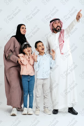 Portrait of a Saudi family looking towards a place, two children standing next to their parents pointing towards a goal, signs of happiness, a happy family atmosphere, the concept of a happy family, spending enjoyable family times