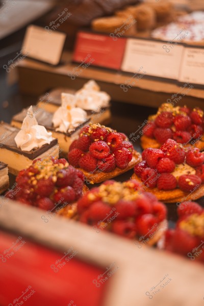 A selection of pastries topped with red raspberries and cream on display in a bakery.