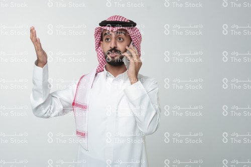 رجل سعودي يقوم بإشارات وهو يتحدث على الهاتف