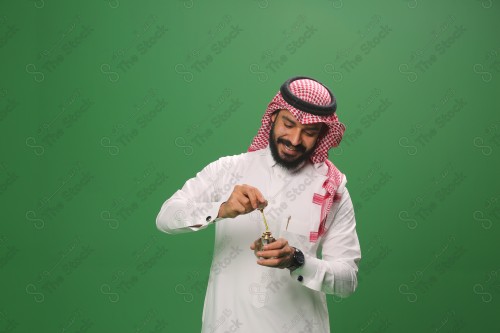 بورتريه رجل سعودي مبتسم يرتدي الزي السعودي التقليدي يحمل زجاجة دهن عود