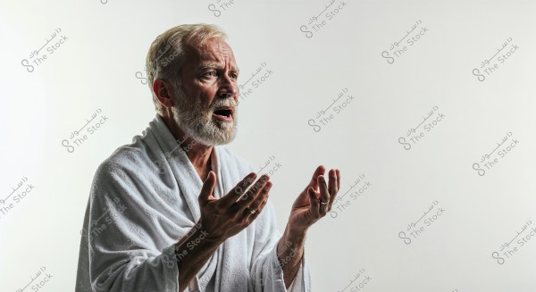 A portrait of an elderly man with white hair and beard, wearing a white robe, appearing to be in meditation or prayer. The man is looking upward with his hands raised, set against a white background.