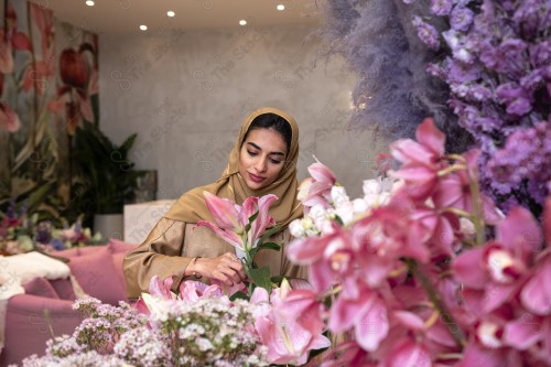 A Saudi woman wearing an abaya working in a flower shop, a bouquet of roses. Holidays and occasions, happy occasions, surprise, Christmas