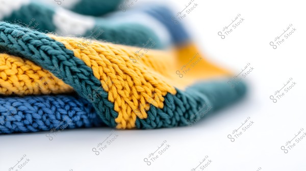 A close-up image of knitted fabric in various colors including blue, green, and yellow. The interweaving of threads is clearly visible in the multicolored fabric, highlighting the details and texture of the knitted yarn.