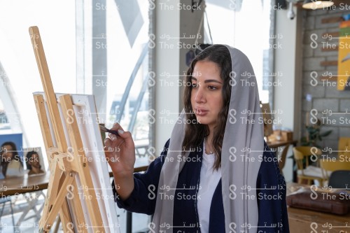 فتاة سعودية ترتدي العباءة ترسم في معمل الرسم