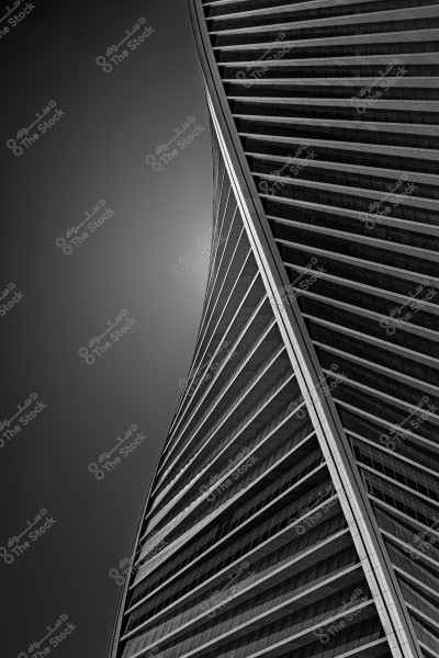 A black and white image of a skyscraper with a twisting, modern architectural design. The building is clearly displayed against a dark sky background, with prominent details of horizontal lines and beams adding a dynamic effect to the stunning design.