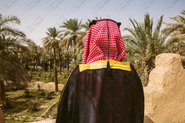 A snapshot of a Saudi man wearing folkloric costume on the day of the foundation stands over a mud building, heritage uniform, on the day of establishment, old archaeological buildings.