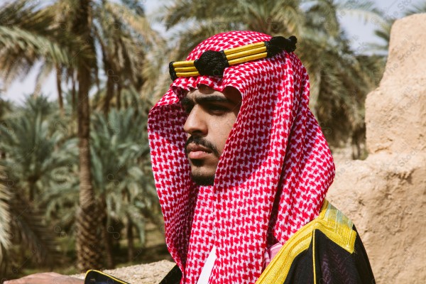 A snapshot of a Saudi man wearing folkloric costume on the day of the foundation stands over a mud building, heritage uniform, on the day of establishment, old archaeological buildings.