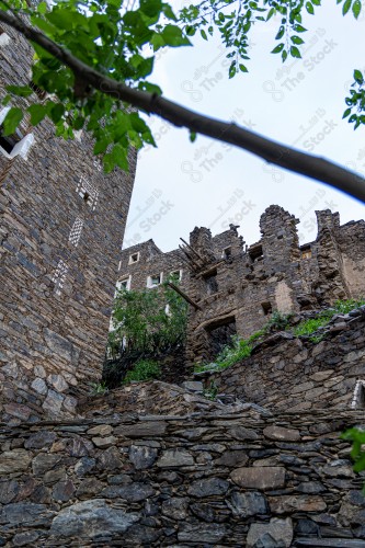 An ancient building built of medium stones, windows surrounded by white paint while the sky looks cloudy at sunset, Rijal Almaa heritage village in the Asir region