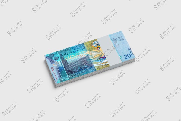 A bundle of 20 Kuwaiti Dinar banknotes placed on a white surface. The design features Kuwait Tower and a dhow with the Kuwaiti flag. The dominant colors are blue and yellow, with intricate details and artistic embellishments.