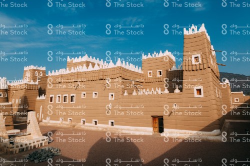 مجموعة من المباني التراثية المبنية من الطين في مدينة نجران وتظهر السماء شبه صافية نهارًا