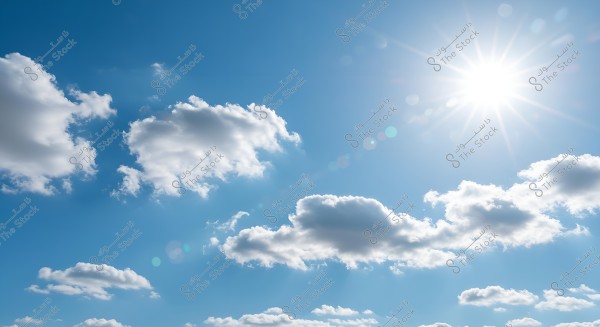 A clear blue sky with scattered white clouds in a bright daytime scene. The sun is visible in the upper right corner, radiating its bright rays with a lens flare effect.