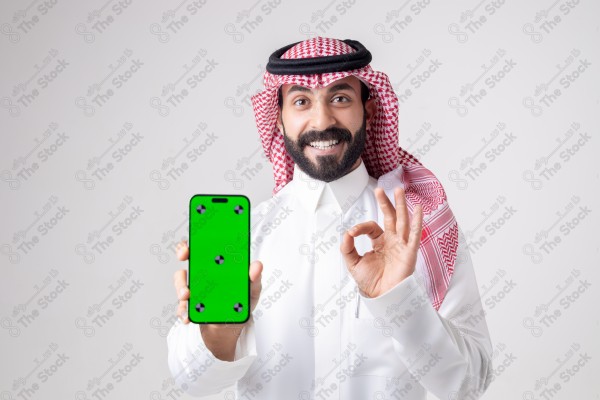 Portrait of a Saudi man holding a phone, pointing at the phone and making different expressions - green screen