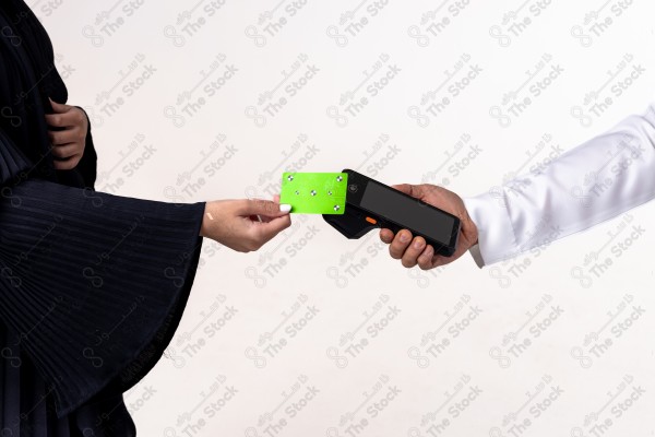 Portrait of a Saudi woman holding a card and making automatic payments on a white background