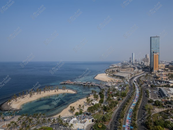 Aerial view of Jeddah Corniche showing the coastline, ocean, and tall buildings in the background.