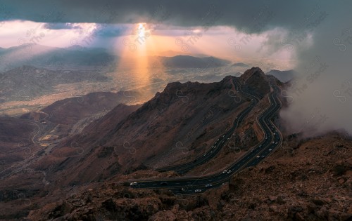 لقطة جوية لسلسلة من الجبال الهدا الصخرية في الطائف نهارًا، مجموعة من الطرقات وسط الجبال