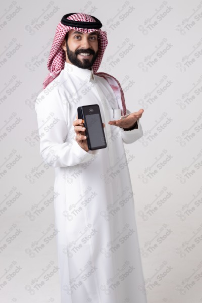 Portrait of a Saudi man holding an automatic payment device and a card and making different expressions