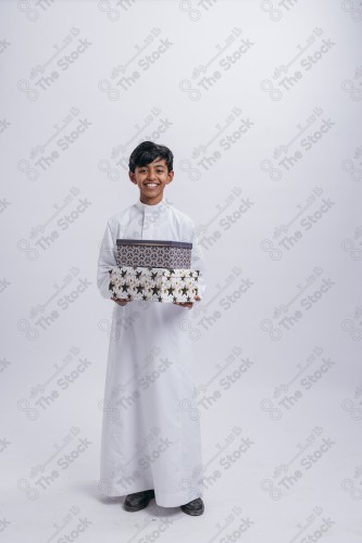 Portrait of a Saudi child on a white background making gestures with his hands while smiling, souvenir photos, ، documenting a happy moment, Eid candy, Eid gifts, Eidiyat, incense