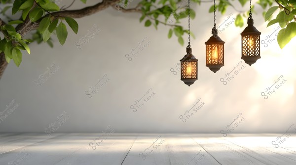 An image of three illuminated metal lanterns hanging from an angled tree branch, with a collection of green leaves visible at the top left of the image. The background is soft and neutral, and the lighting creates gentle shadows on the pale wooden floor below.