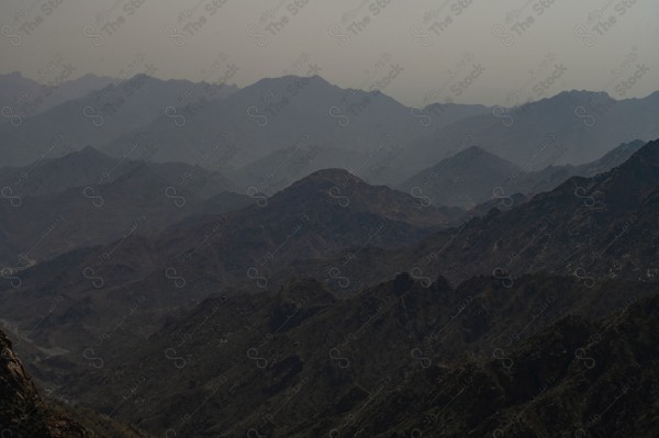 A shot of a series of rocky mountains and off-road roads extending through the mountain in the city of Taif. The sky is overcast in western Saudi Arabia, the rocky mountain range, nature in Saudi Arabia.